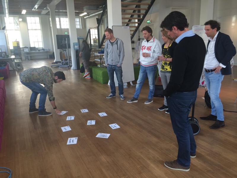 Een team werkt staand met kaartjes op de vloer